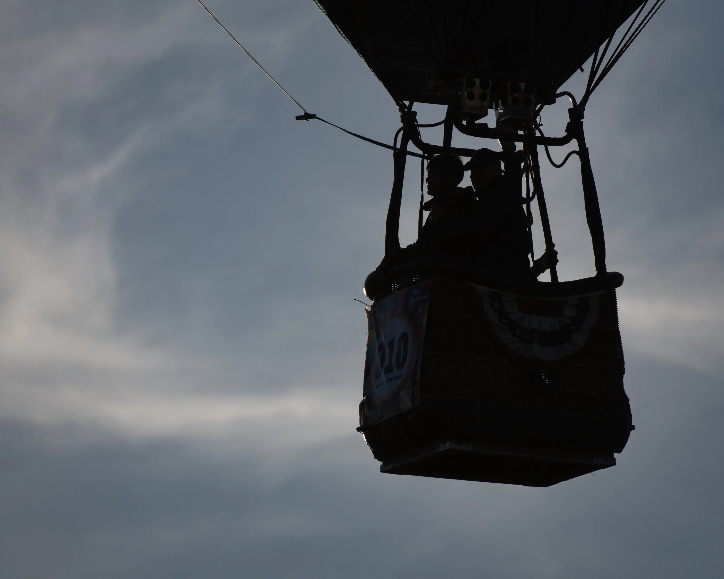 Una canasta de globo aerostático a contraluz con un cielo nublado de fondo. (c) 2025 Héctor Obregón