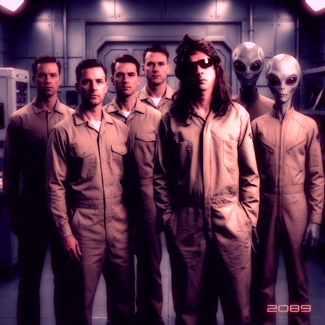 Six men in beige jumpsuits and two aliens with large heads and big black eyes, standing in a sci-fi setting with machinery in the background, and the year 2089 in the bottom corner.