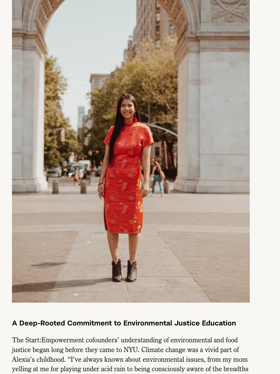 A woman in a red cheongsam dress standing outdoors in front of a large archway with trees and city buildings in the background.