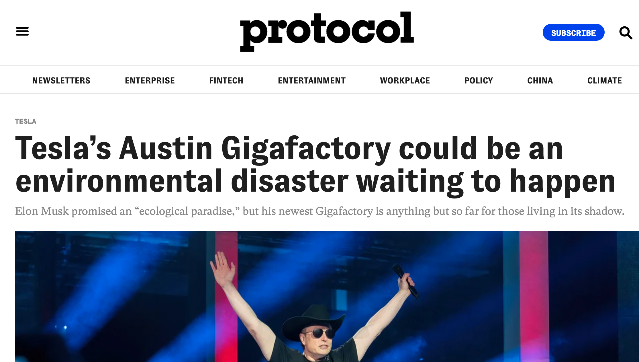 Screenshot of an article on a website named 'protocol' with a headline about Tesla's Austin Gigafactory, mentioning environmental concerns. The image below the headline shows Elon Musk wearing sunglasses and a cowboy hat, raising his arms on a stage 
