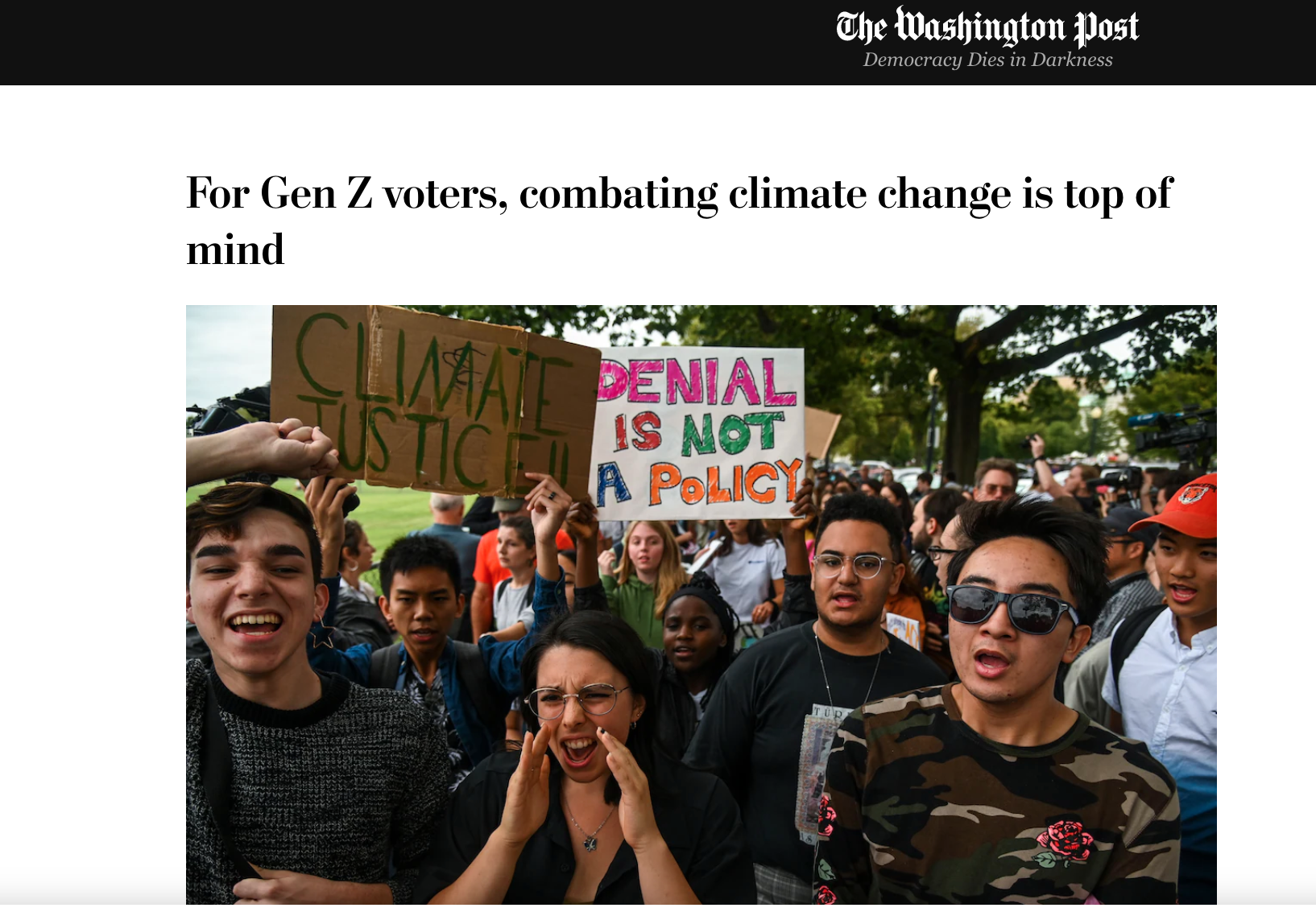 Group of young people protesting outdoors, holding handmade signs with messages about climate change and climate justice.