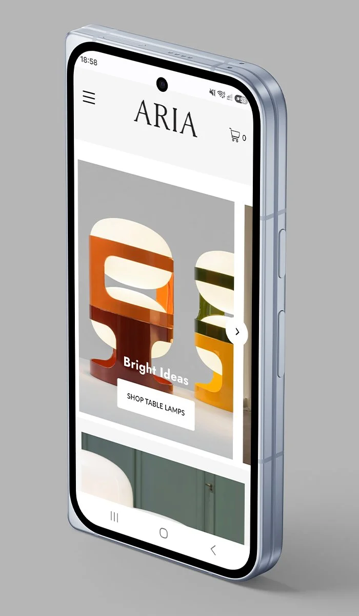 A smartphone displaying a website called ARIA with a section labeled Bright Ideas featuring colorful table lamps and a button to shop for table lamps.