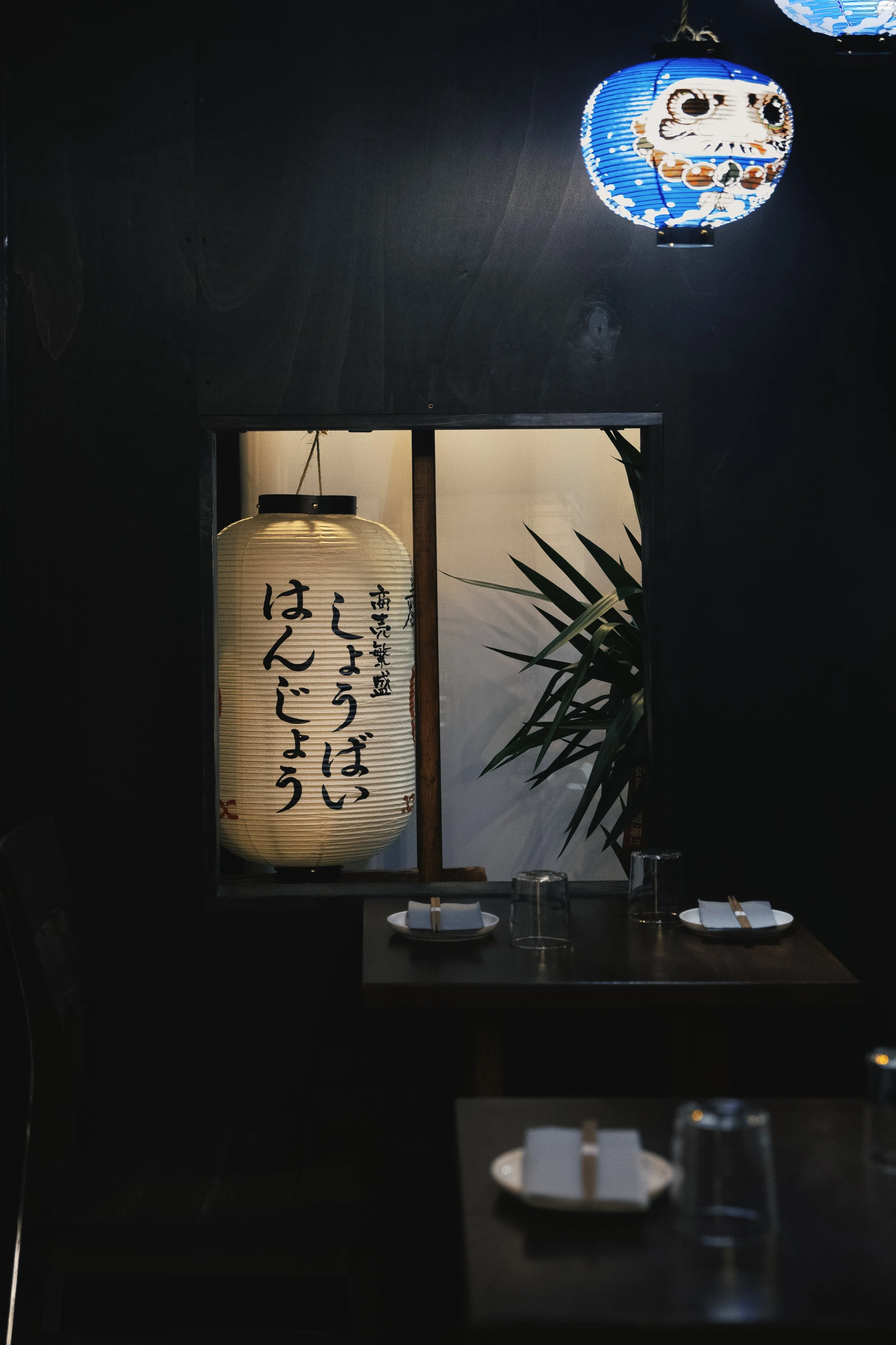 Interno di un ristorante giapponese con lanterne tradizionali e decorazioni minimaliste.