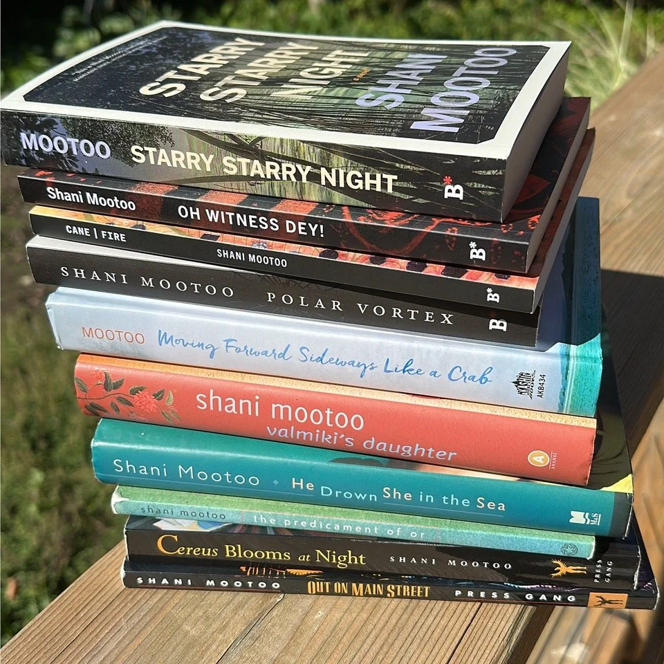 Stack of books by Shani Mootoo on a wooden surface outdoor. Titles include: Starry Starry Night, Oh Witness Dey!, Cane|Fire, Polar Vortex, Moving Forward Sideways Like a Crab, Valmiki's Daughter, He Drown She in the Sea, and others