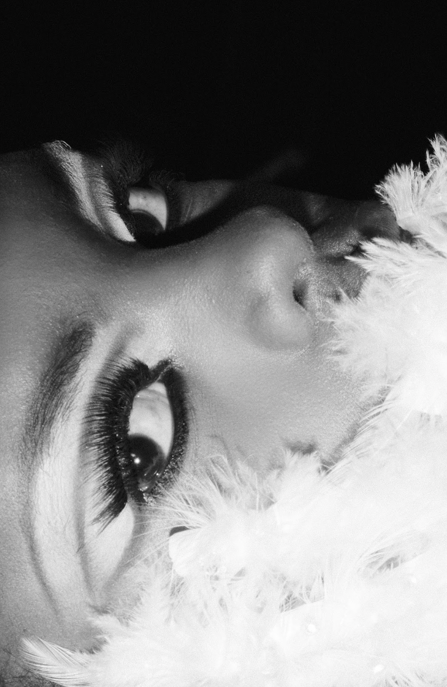 Close-up of a woman's face lying on a soft, fluffy surface, in black and white.