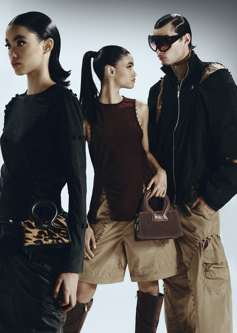 Three models posing in fashionable outfits and accessories, each holding handbags, with a plain background.