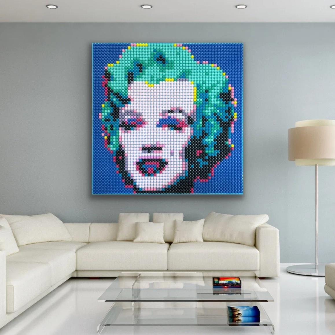 A large pixel art portrait of a woman with short, wavy, colorful hair, hanging on a gray wall in a modern living room with white furniture and a glass coffee table.