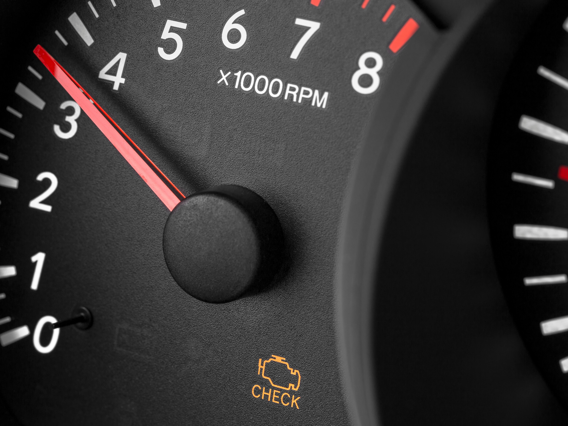 Close-up of a car dashboard showing a tachometer with the needle pointing to around 3.9, and a yellow check engine light indicator with the text 'CHECK'.