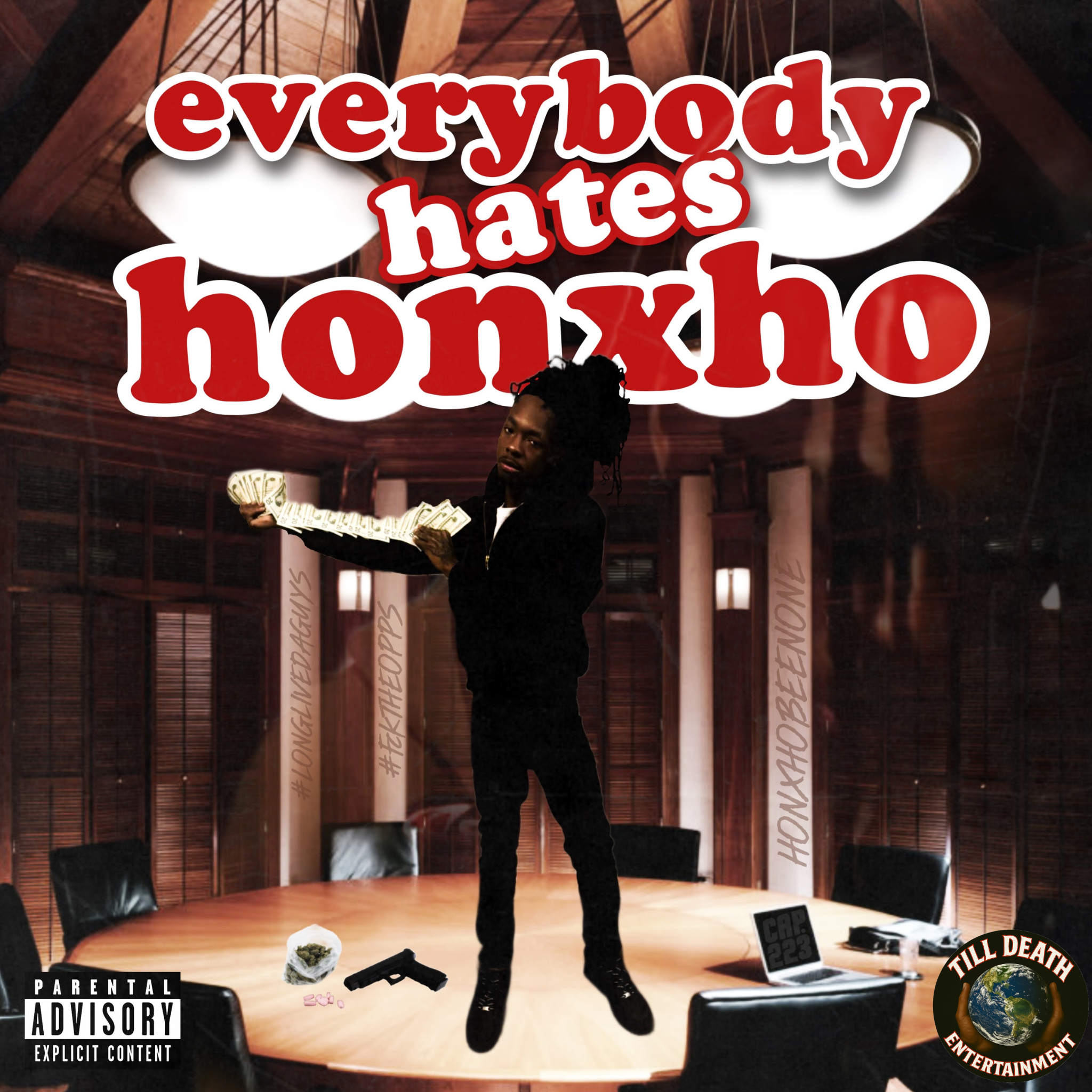 A person standing on a stage holding a stack of money, with a background of wooden beams and a large screen displaying the words "everybody hates bourgeois." There are various objects on the floor, including a gun, a cat, and various stickers and labels, including a 'Parental Advisory' sticker and a globe with the message 'Till Death Do Us Part' and 'Entertainment'.