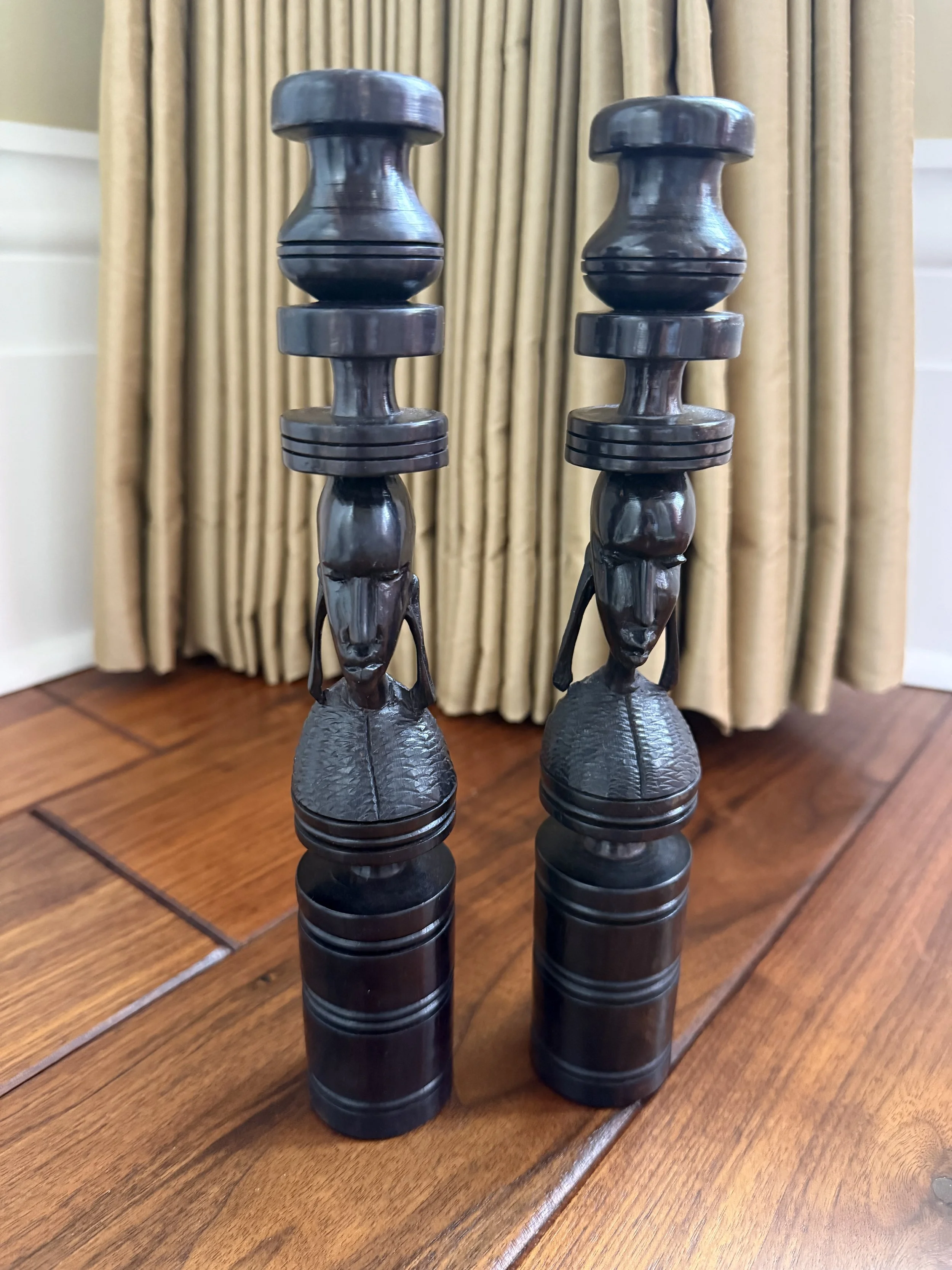 Pair of hand-carved African ebony wood candle holders, featuring Maasai tribal faces