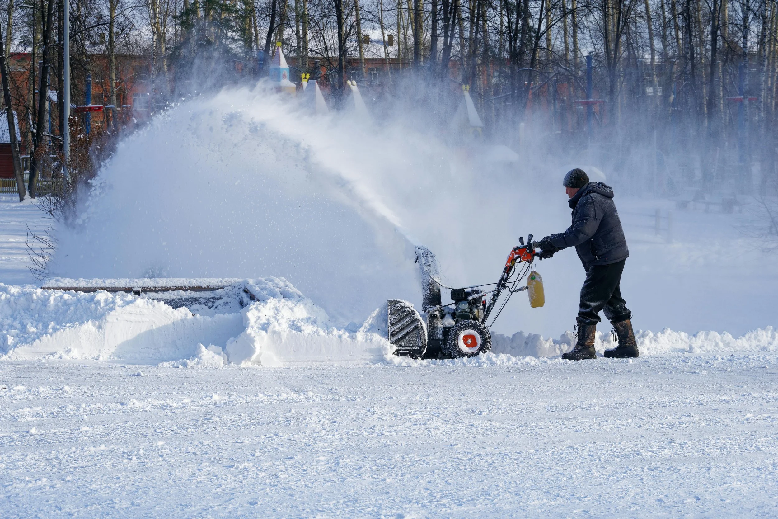 A person using a snow blower to clear snow from a field during winter.