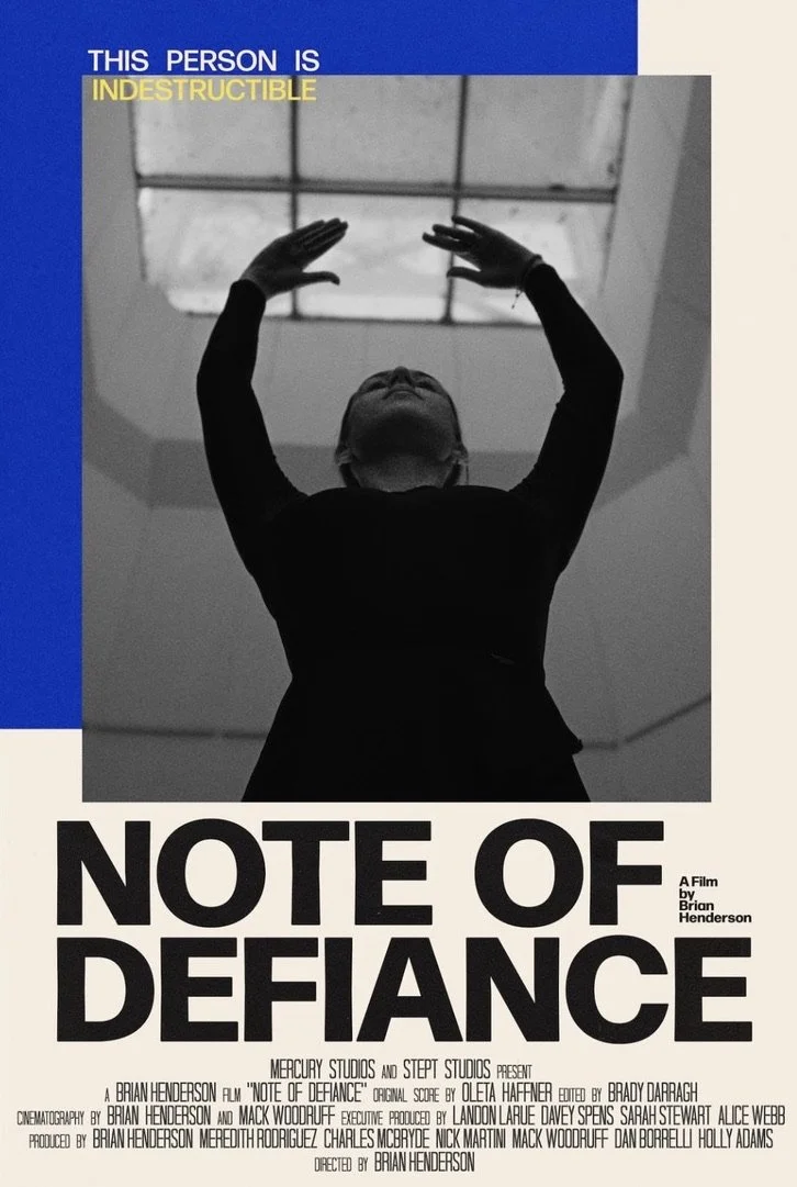 Film poster for 'Note of Defiance' showing a person in black clothing with hands raised toward a skylight, with text indicating they are 'indestructible'.