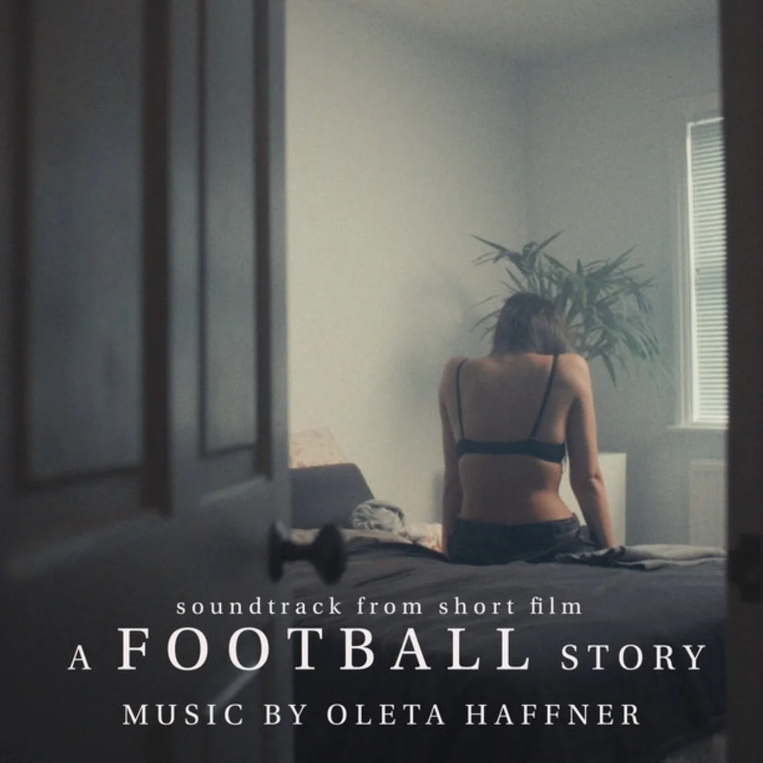 A woman sitting on a bed in a dimly lit room, viewed through a partially open door, with the text 'soundtrack from short film A FOOTBALL STORY Music by Oleta Haffner' overlaid.