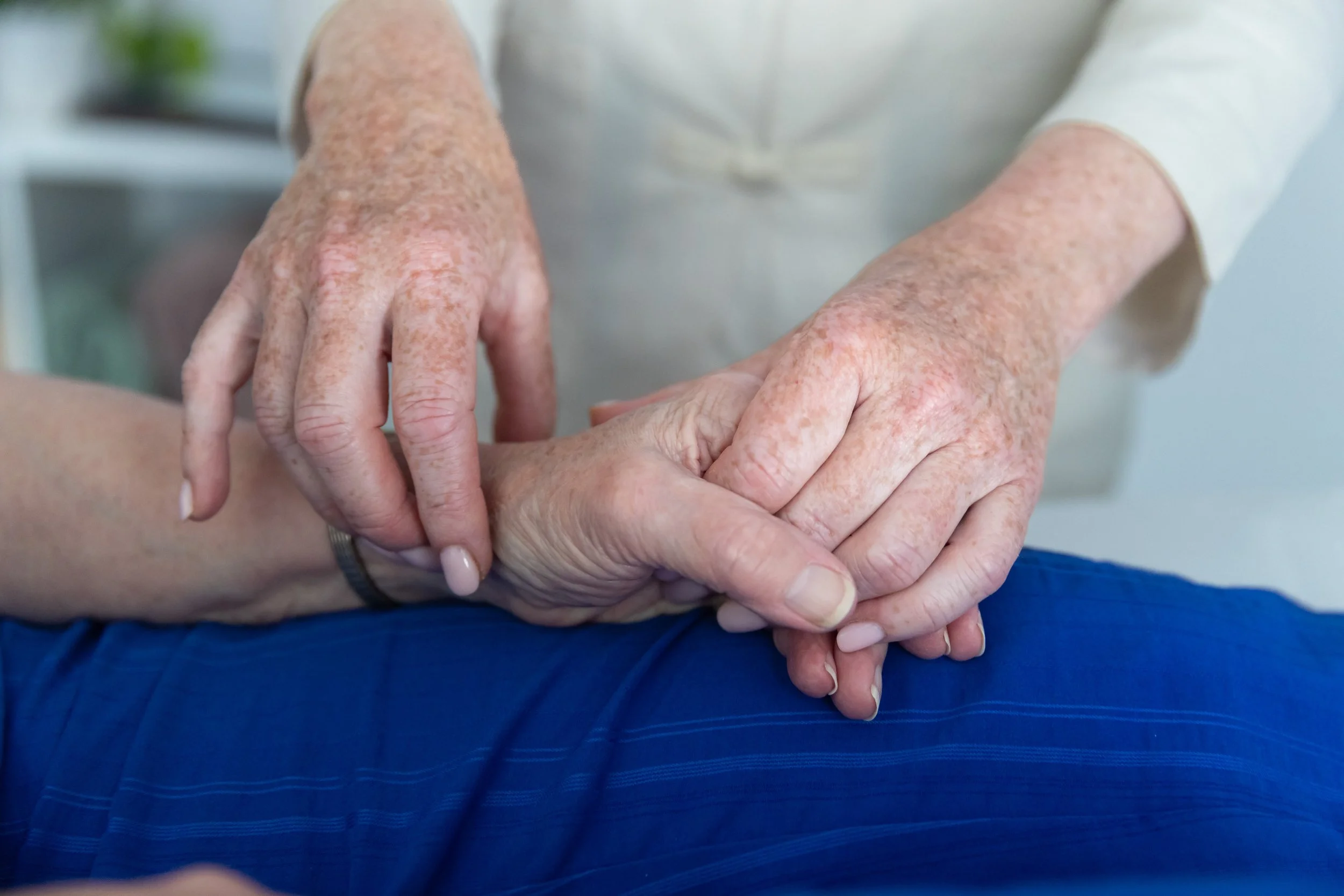 Close-up of a healthcare worker holding an elderly person's hand, demonstrating care and compassion.