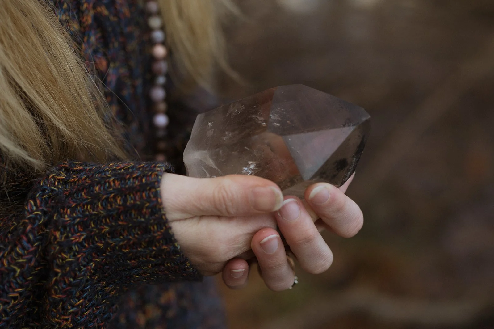 Person holding a large, clear quartz crystal.
