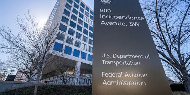 A large black sign in front of a modern office building displays the address 800 Independence Avenue, SW, and the names of the U.S. Department of Transportation and Federal Aviation Administration.