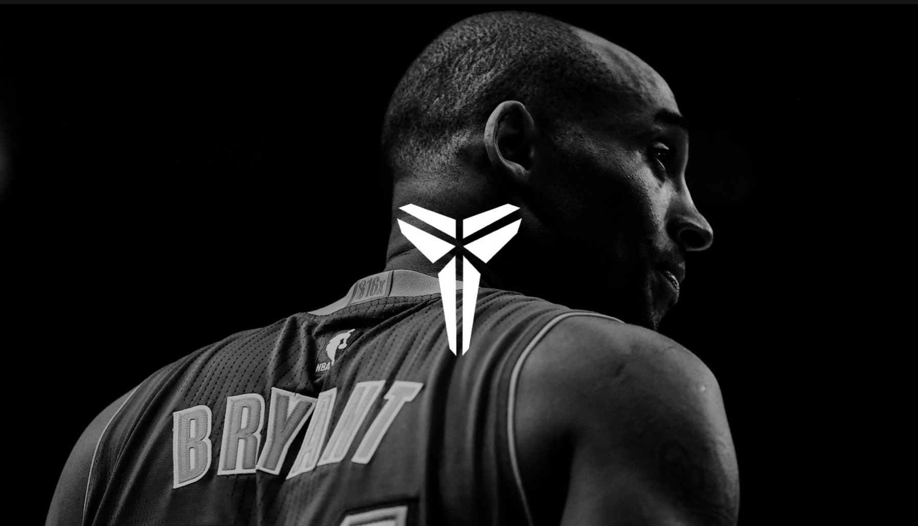 Close-up black and white photo of NBA player Bryant, seen from behind, showing his name on the jersey and a logo in the center of the image.