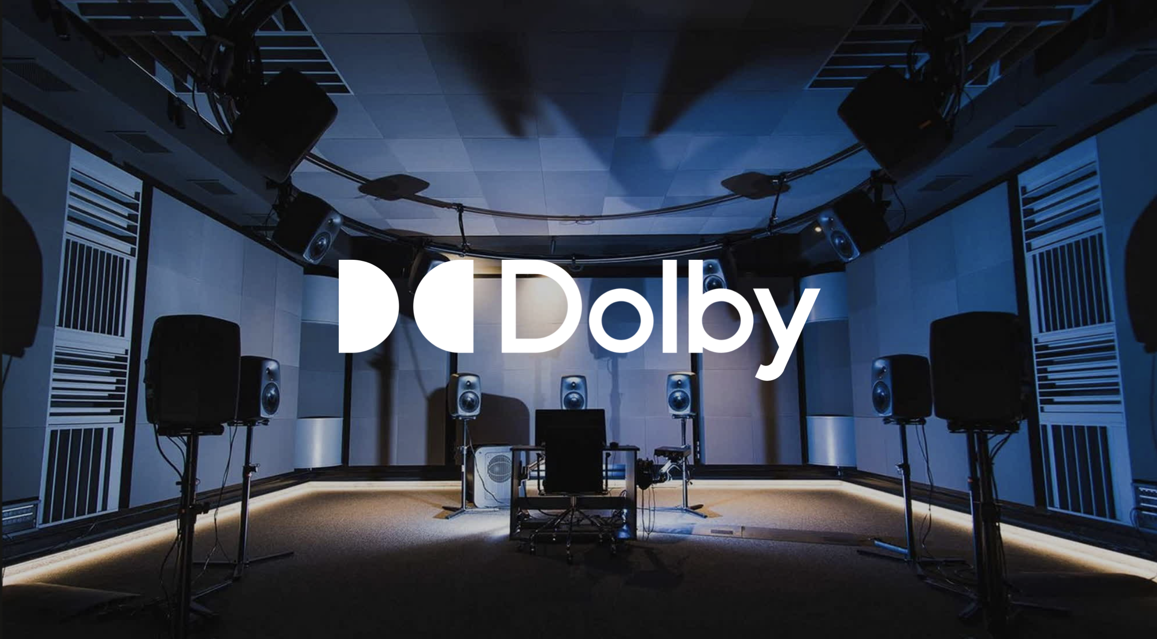 A recording studio with multiple speakers and microphones set up around a mixing console and computer, with a large 'Dolby' logo overlayed.