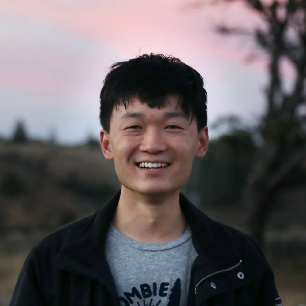 Headshot of Jeffery Chen. He is wearing a dark colored jacket on top of a medium gray shirt.