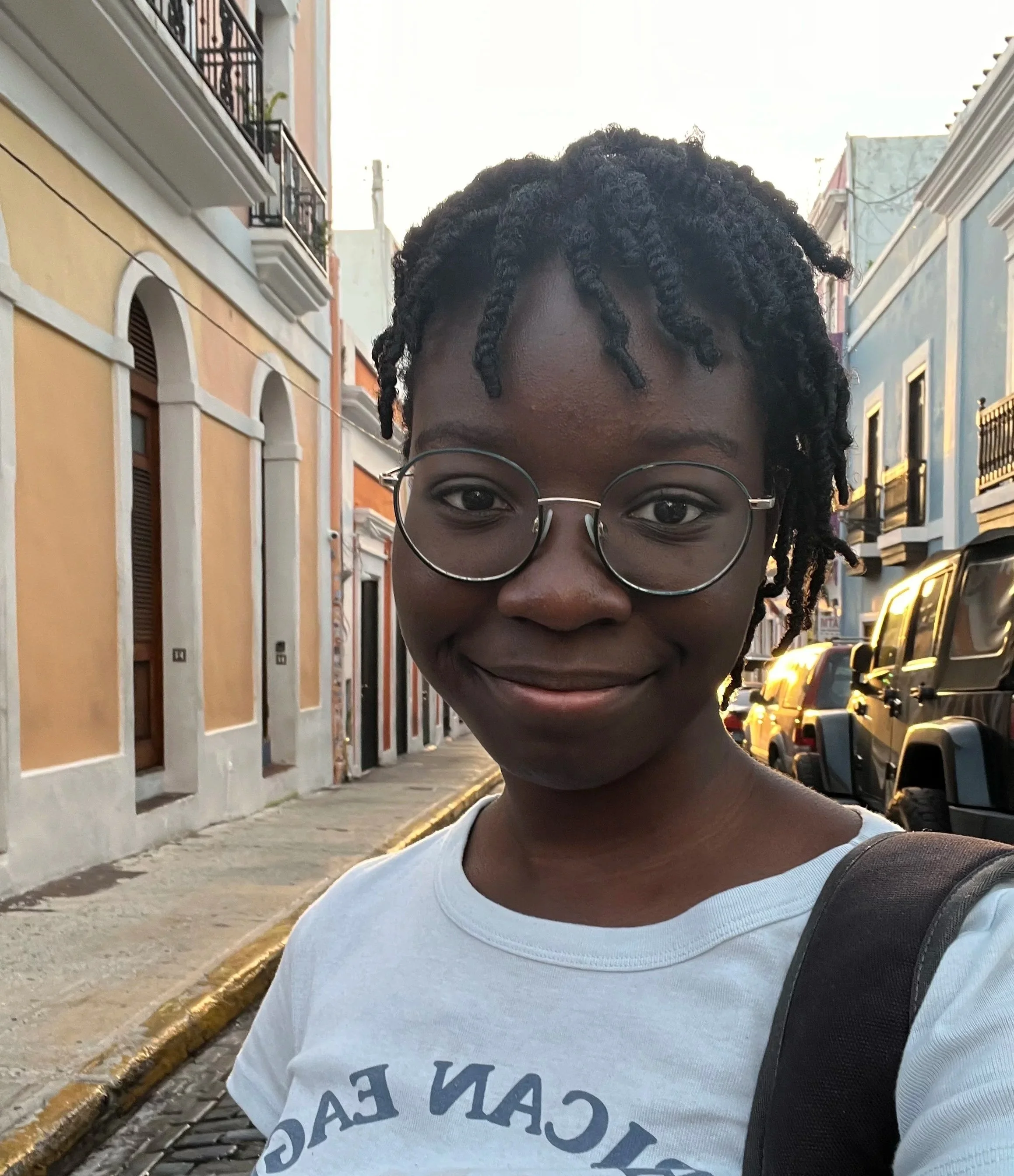 Headshot of Amira Adarkwah wearing a light blue shirt and a dark backpack strap on her left shoulder.
