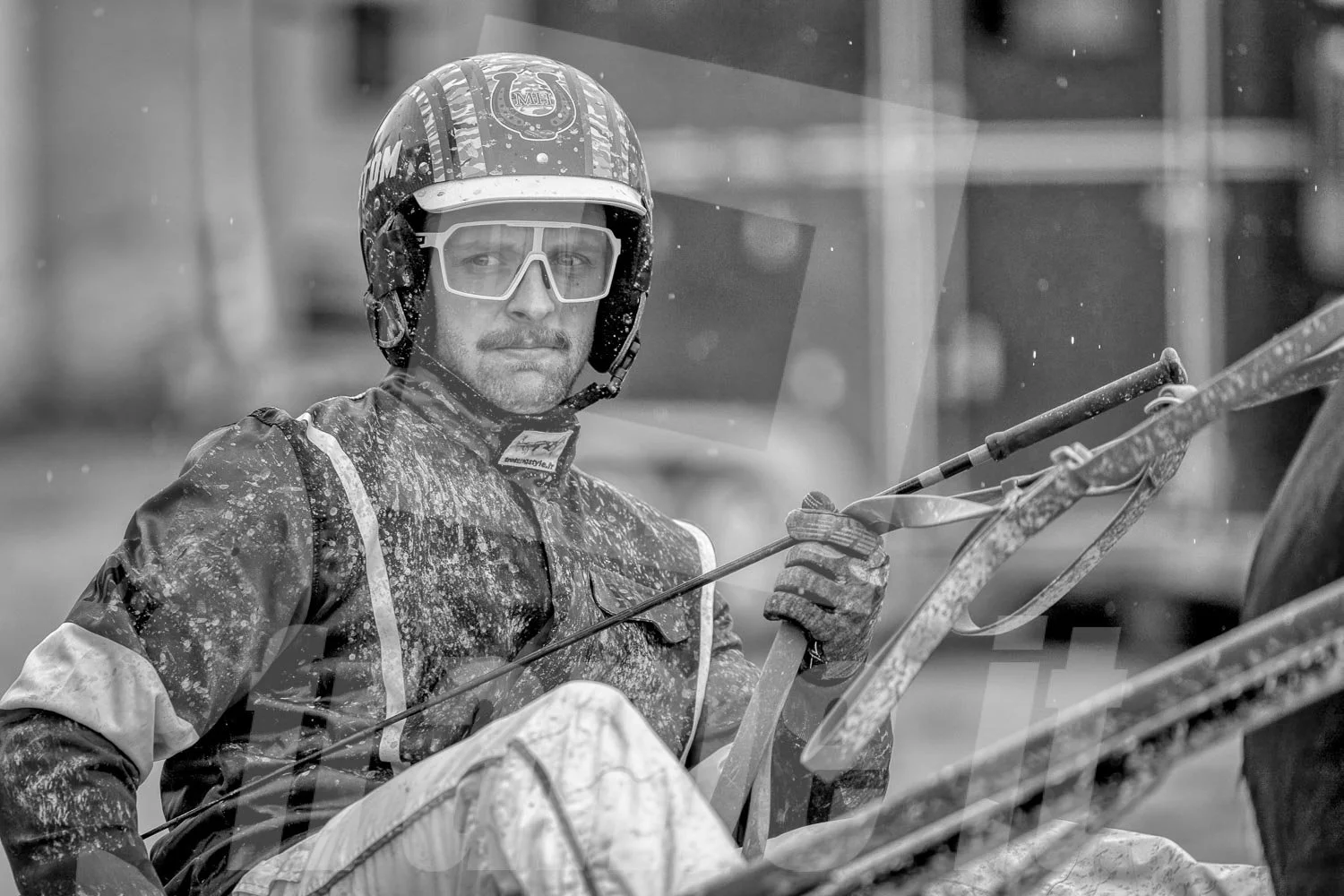 Trabrennfahrer in der WIener Krieau. Das Bild ist schwarz-weiß, im Hintergrund unscharf.