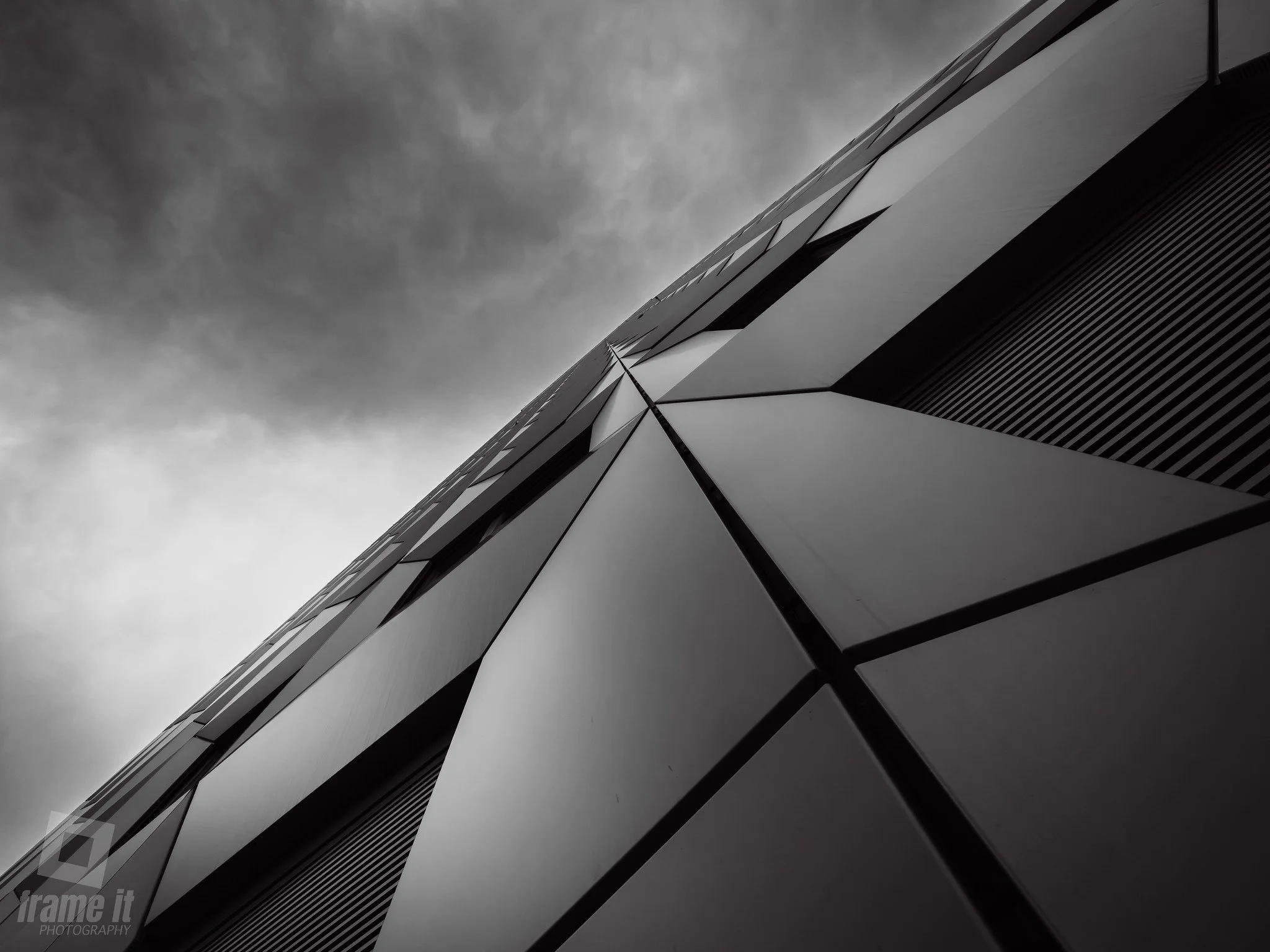 Nahaufnahme eines modernen Gebäudes in Wien mit geometrischen Mustern an der Außenseite, aufgenommen von unten im Schwarz-Weiß-Stil.