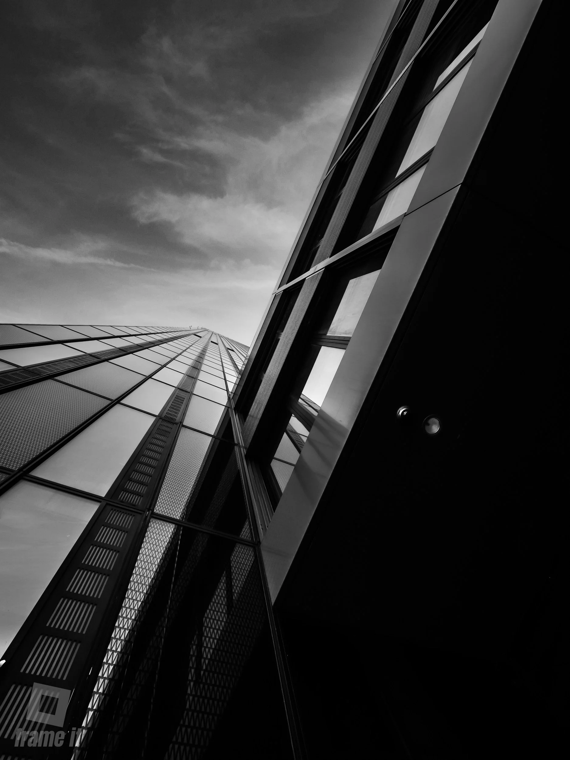 Ein hoch aufragendes modernes Bürogebäude, die Rückseite des DC Towers in Wien, mit reflektierenden Glasfenstern, fotografiert aus einer tiefen Perspektive gegen den Himmel.