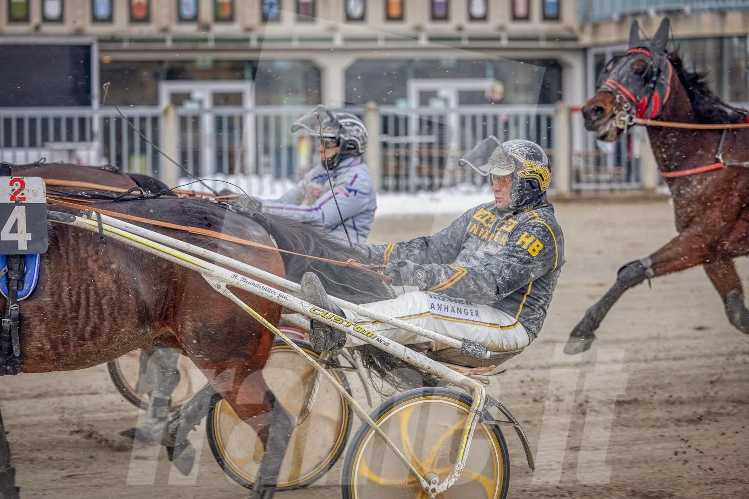 Pferderennen auf einer Rennbahn bei winterlichen Bedingungen, mit zwei Fahrern.