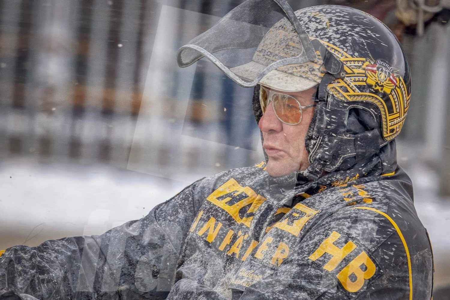 Trabrennfahrer mit schwarzen Helm und einer schwarzen Jacke mit gelben Aufnähern auf der Trabrennbahn Wien Krieau.