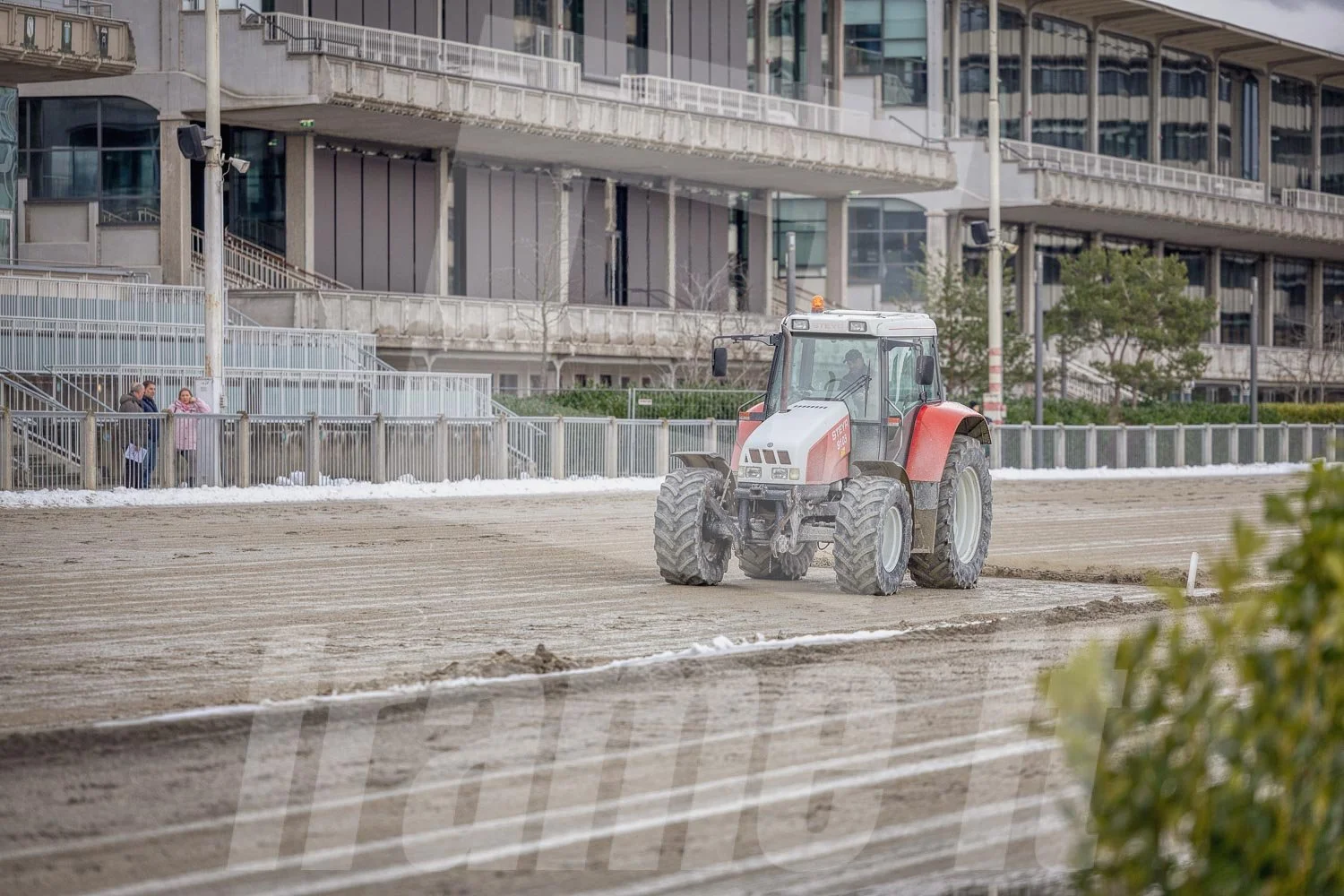 Ein roter Traktor auf einer Trabrennbahn.