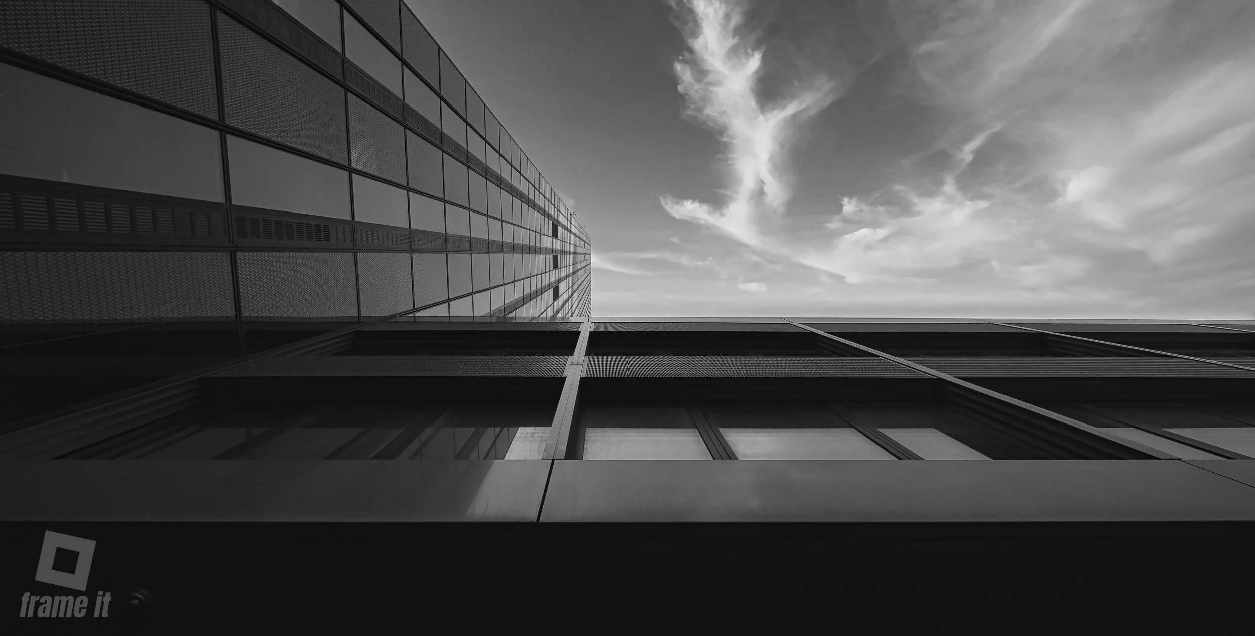 Aufnahme eines modernen Gebäudes, dem DC Tower, mit Glasfenstern, aufgenommen von unten nach oben, mit einer dramatischen Wolkenformation am Himmel