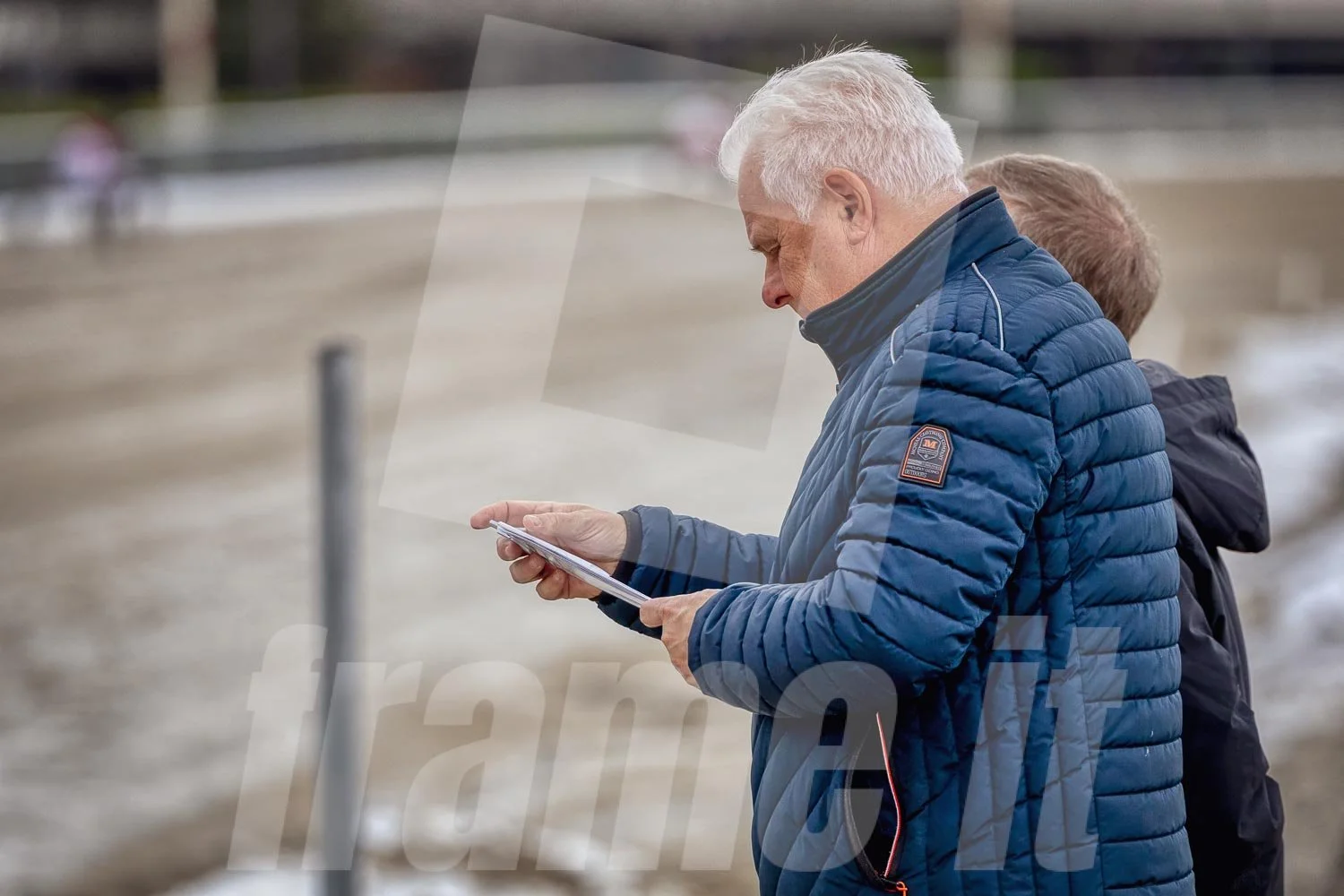 Trabrennpark Krieau in Wien. Ein älterer Mann sieht auf sein Handy.