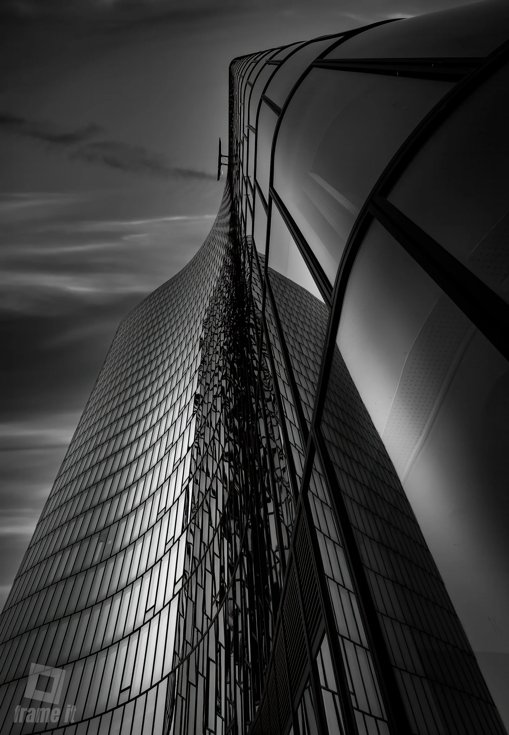 High-rise moderne Glasfassade eines Gebäudes, fotografiert von unten, schwarz-weiß, dramatischer Himmel im Hintergrund.
