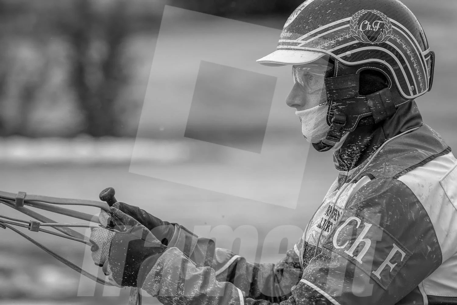 Ein Trab-Rennfahrer in Schutzhelm und Schutzkleidung, in Profilaufnahme, schwarz-weiß.