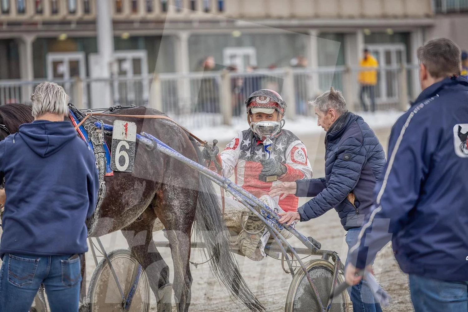 Sieger im Trabrennen hält Trophäe, umgeben von Teammitgliedern, Trabrennpark Krieau.