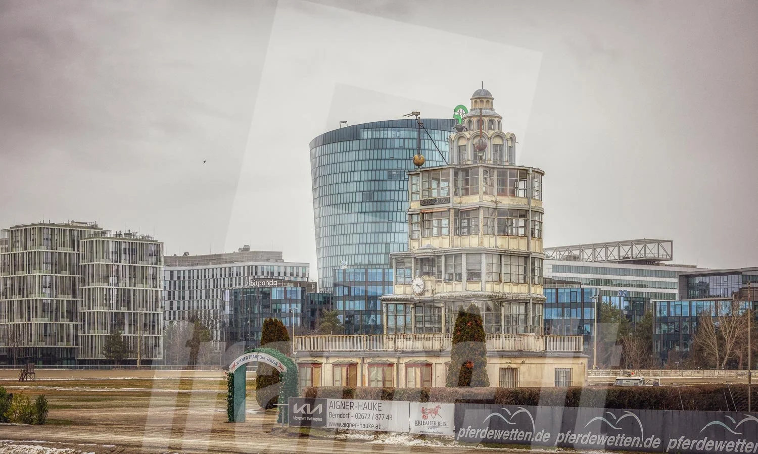 Historischer Richterturm der Trabrennbahn Krieau in Wien, mit modernen Gebäuden im Hintergrund.