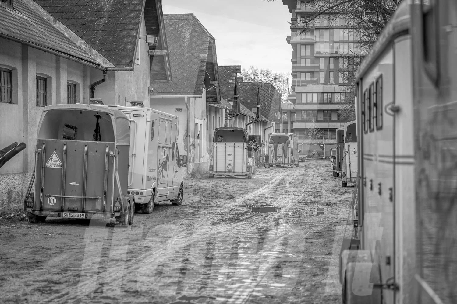 Blick auf eine enge, ungepflasterte Straße in der Wiener Krieau, bei schlechtem Wetter in Schwarz-Weiß.