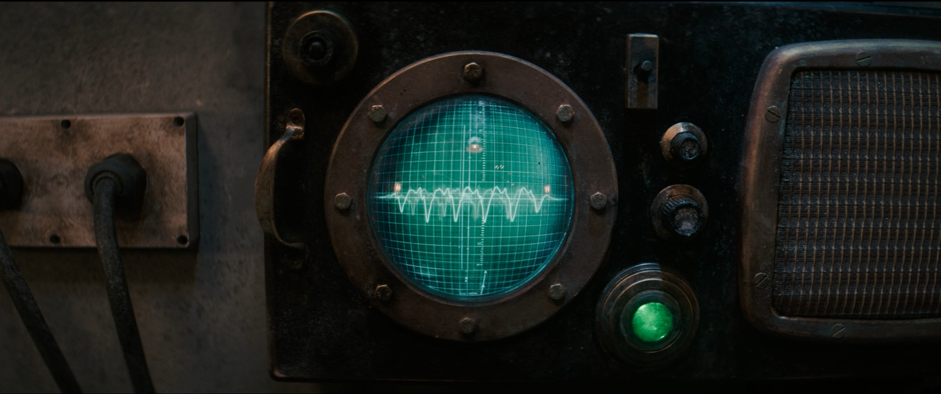 A vintage radar or sonar display with a green glow, showing a grid and wave pattern, surrounded by metal and mechanical components.