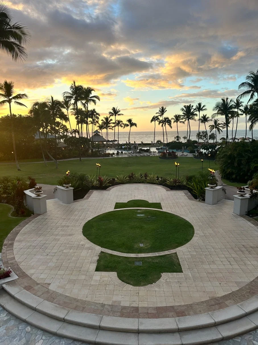 Hotel grounds at luxury resort in Hawaii. Palm trees, pool, and the ocean.