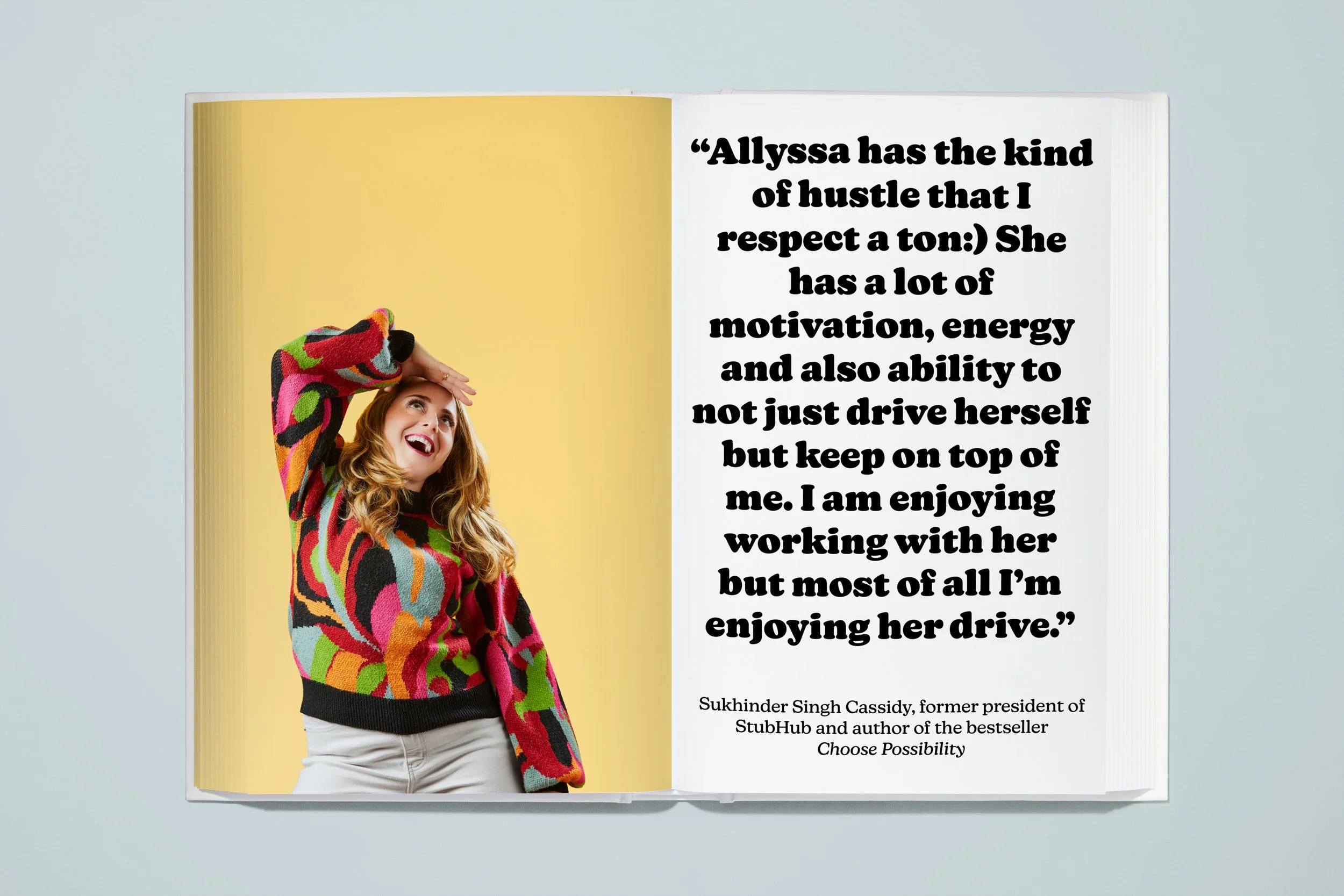Open magazine with a photo of a woman with red hair wearing a colorful patterned sweater, laughing and touching her forehead, on the left page. Right page contains a quote from Sukhinder Singh Cassidy about Allyssa, her motivation and drive.