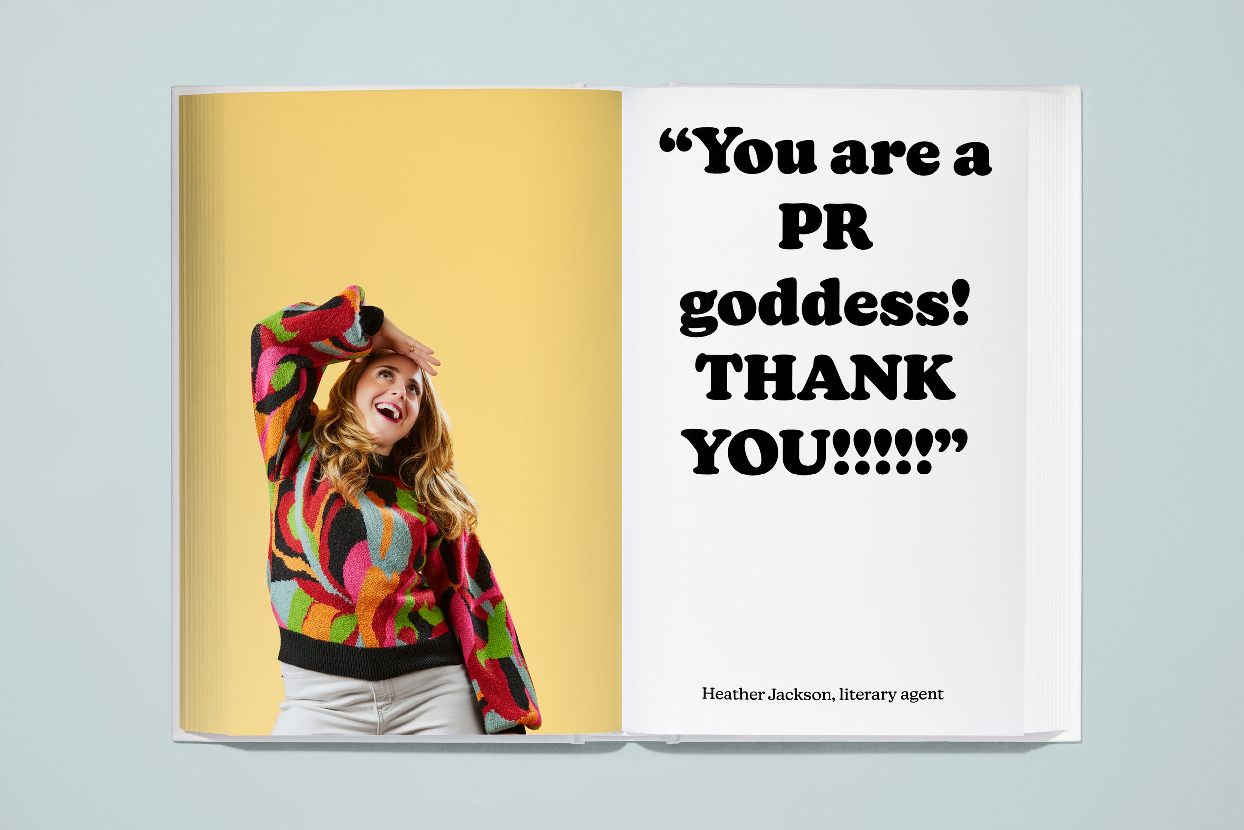Open book with a woman wearing a colorful, patterned sweater, smiling and holding her hand to her forehead, standing against a yellow background on the left page. The right page contains large, bold text reading "You are a PR goddess! THANK YOU!!!!!"