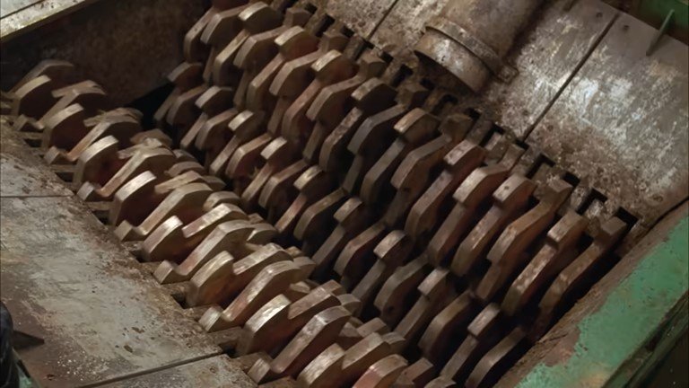 Close-up view of a machine with multiple metal curved blades arranged in rows, likely used in industrial manufacturing or processing.