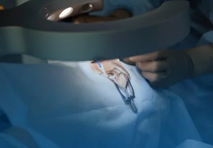 Medical procedure involving a surgical instrument and a healthcare professional's gloved hand.