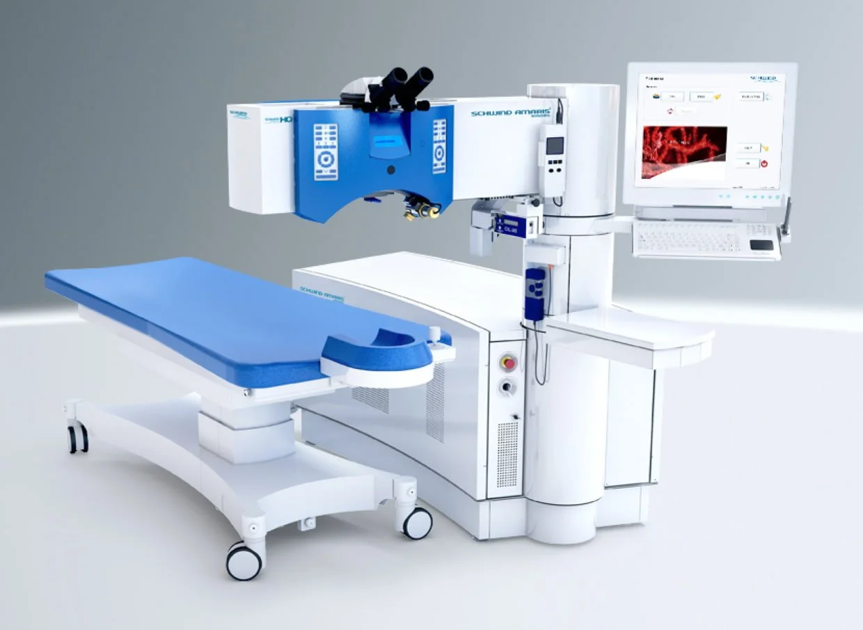 Medical laboratory equipment with a microscope, a patient bed, and a computer monitor showing a red image.
