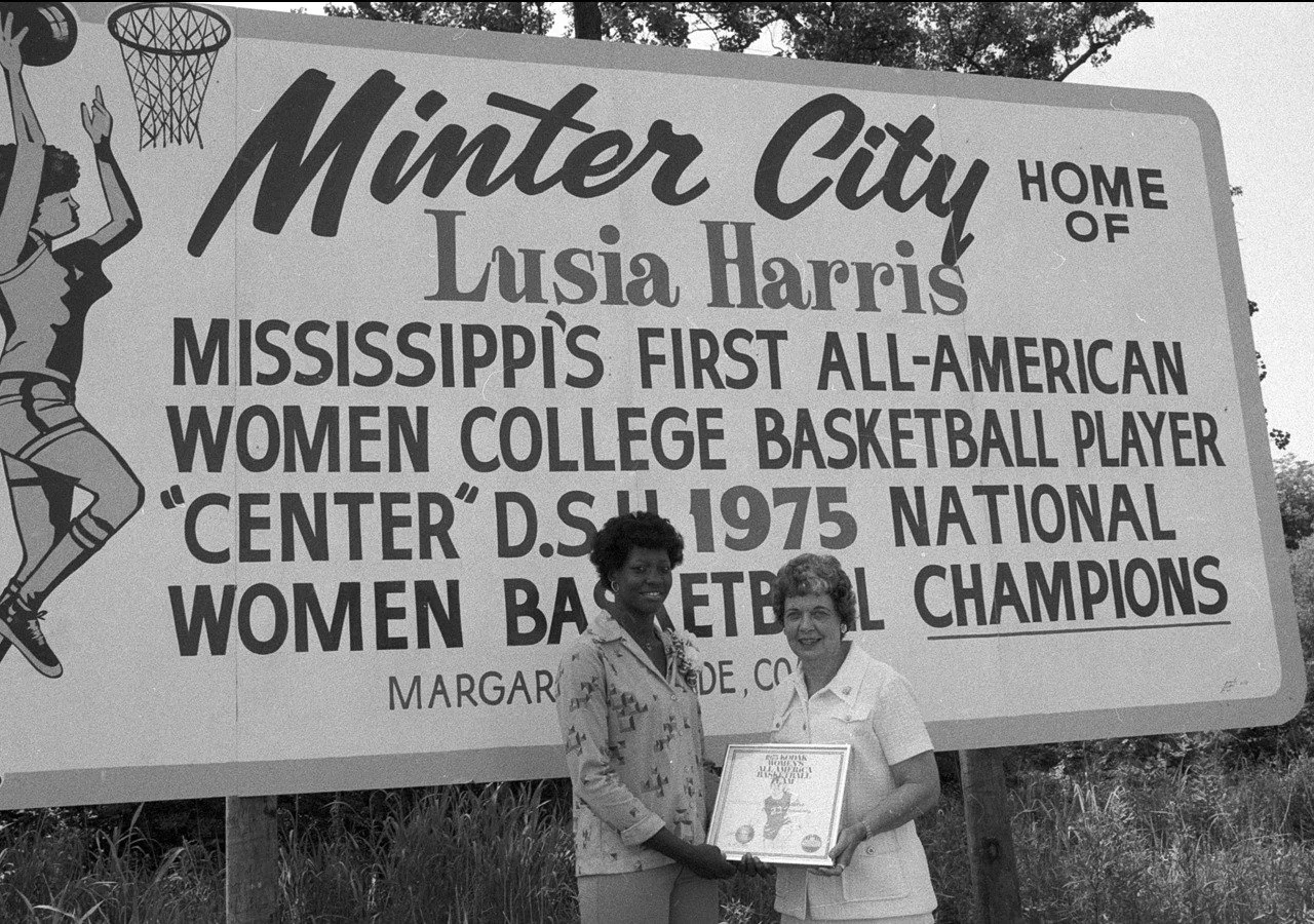 The great coach Margaret Wade and Lucy Harris are standing in front of the sign the citizens of Minter City erected in Lucy's honor. Unfortunately the sign is no longer there.