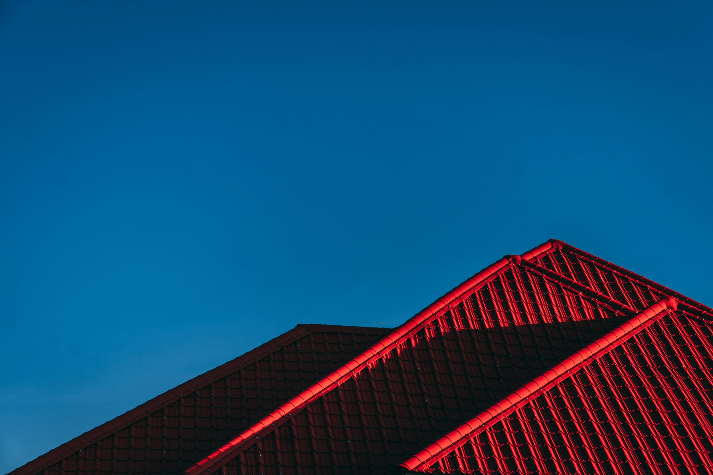 Close-up of a red tiled roof against a clear blue sky.