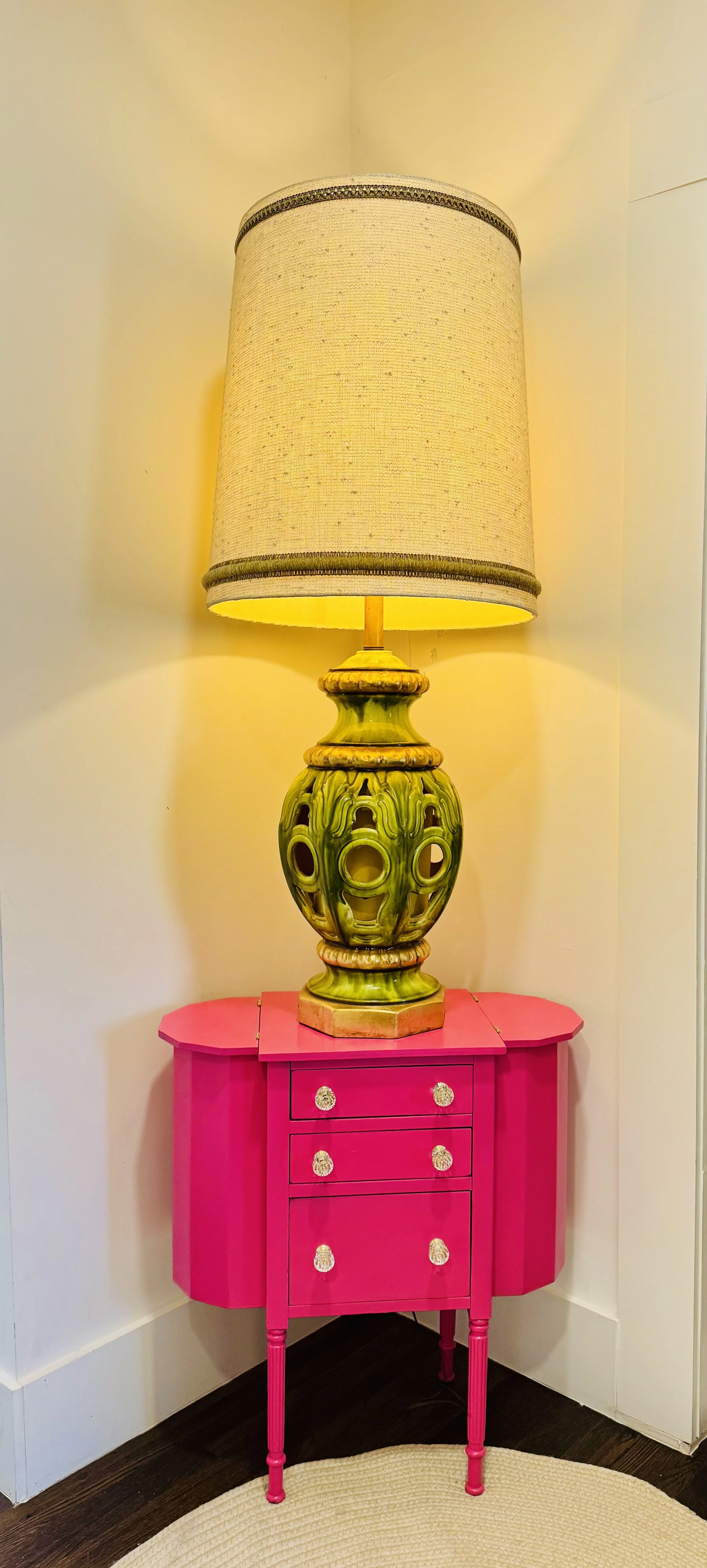 Mid-century ceramic table lamp featuring a pierced base with green and gold drip glaze, reminiscent of 1960s 1970s Majolica style lighting. Paired with a vintage Martha Washington sewing table reimagined in a bold hot pink finish.