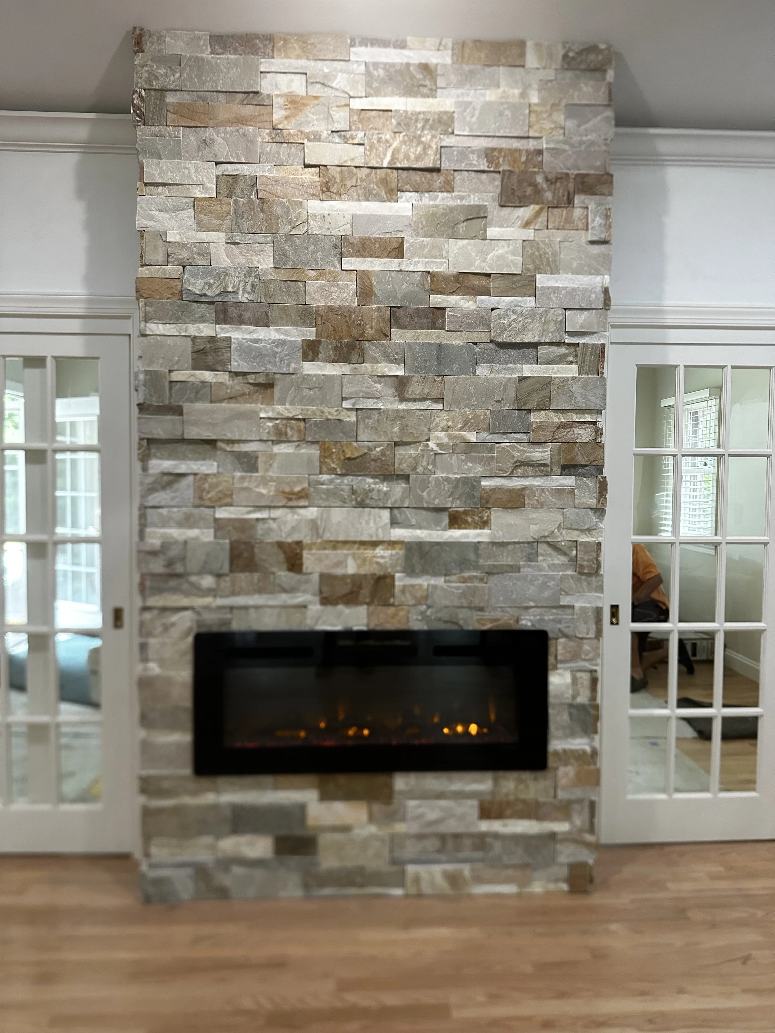 Stone fireplace wall with electric fireplace insert in a living room.