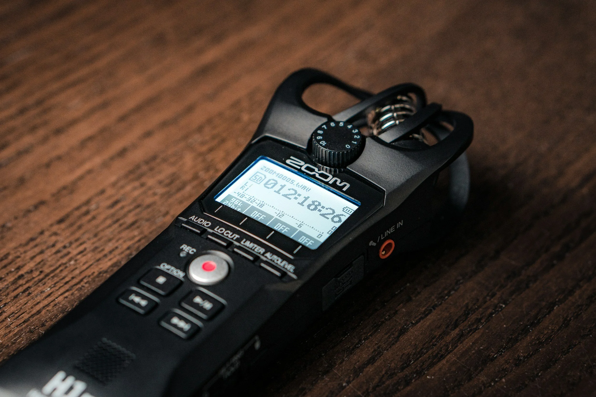 A Zoom audio recorder placed on a wooden surface.