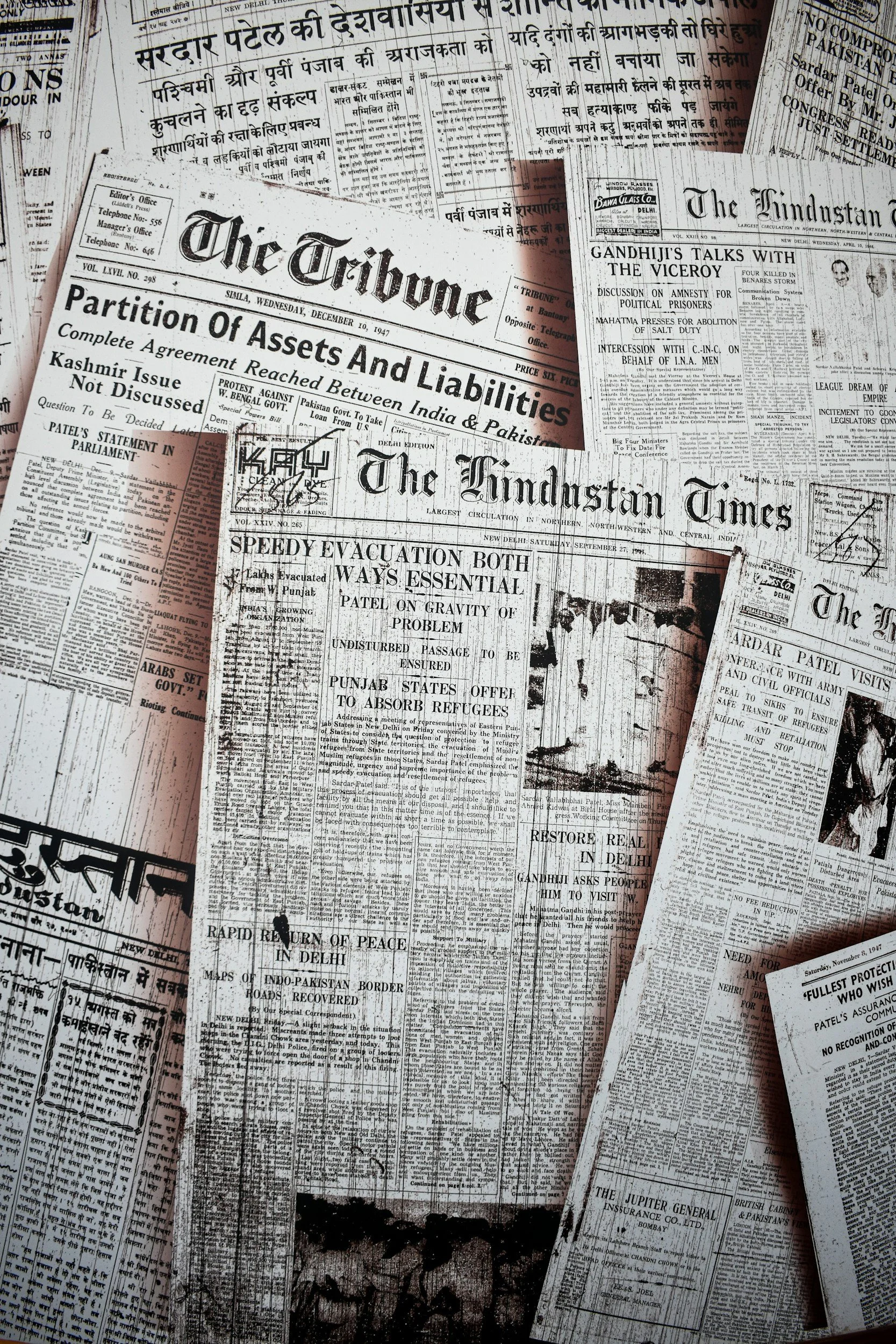 A collage of old newspaper pages with headlines and articles in Hindi and English, including titles like "Partition of Assets and Liabilities" and "Speedy Evacuation Both Ways Essential," from various dates.
